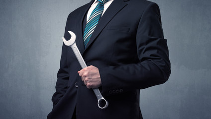 Young, handsome, cute businessman holding tool with grey background