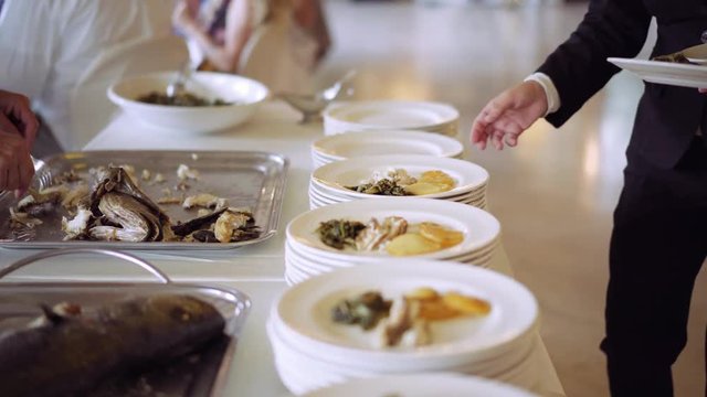 Professional chefs in a restaurant preparing large numbers of food fish with potato. Dinner in a restaurant. Seafood. Serving table. Healthy food. Catering service. 4K (UHD).