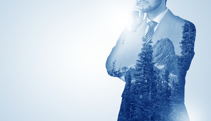 Young businessman standing and meditate with trees on the background 