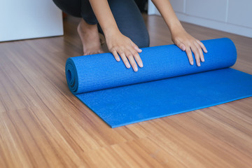 Woman hands rolling or folding blue yoga mat after a workout,Exercise equipment