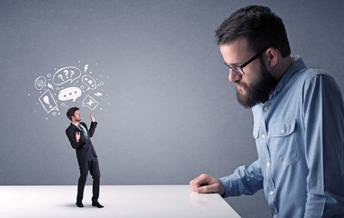 Young professional businessman being angry with an other miniature businessman who has drawn speech and thought bubbles above his head