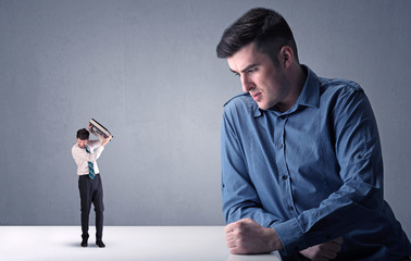 Young professional businessman being angry with an other miniature businessman in front of a...