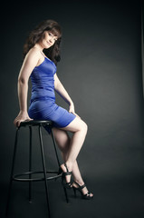 Beautiful brunette in blue dress posing in studio.