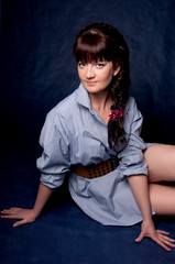 Beautiful brunette in a man's shirt posing in the studio.