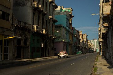 Un auto muy antiguo pasa por una calle muy sola. 