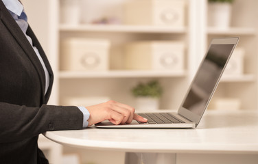 Business woman below chest working on her laptop in a cozy environment
