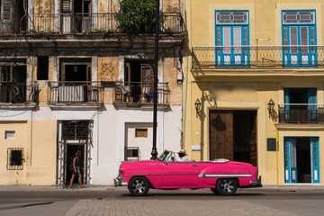 Un carro antiguo de color rosado circula por el casco histórico de la Habana.