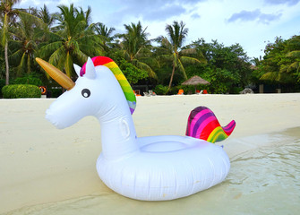 A rainbow unicorn plastic pool float on the beach  © eqroy