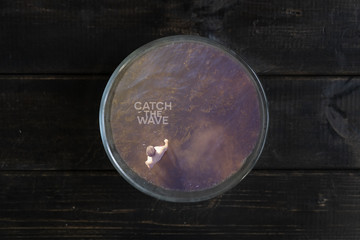 young man surf rider in sea inside of cup on the wooden surface, a surfing concept idea