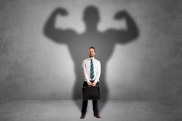 Lovely serious businessman standing with a muscular powerful shadow behind his back
