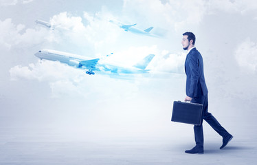 Obraz premium Elegant businessman going somewhere with briefcase and airplane on the background 