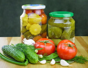 Pickled tomatoes and cucumbers in glass jars