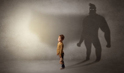Cute kid in a room with plush on his hand and hero shadow on his background
