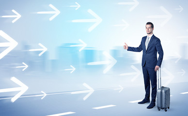 Young businessman hitchhiking near the city with arrows around concept