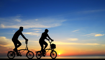Obraz premium Silhouette group friend and bike relaxing on blurry sunset background.