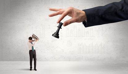Little businessman is afraid to make the next step in his chess game with graphs, charts and...