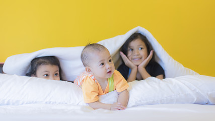 childden are enjoying funny time indoor in modern yellow bed room.