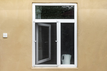 An open window with a mosquito net in the wall of the house