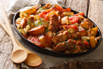 Georgian dinner: fried meat with potatoes, tomatoes, onions, herbs and spices close-up on a frying pan. horizontal