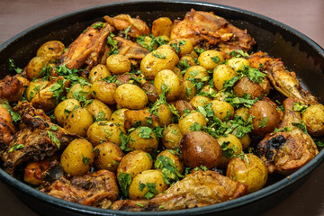 Roast , potatoes with chicken and italian parsley in a baking tray.