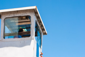 A man controlling a ferry boat from the old tower with blue sky background