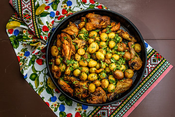 Roast , potatoes with chicken and italian parsley in a baking tray.
