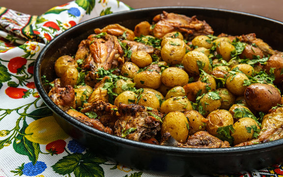 Roast , potatoes with chicken and italian parsley in a baking tray.