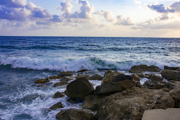 Landscape of the sundown in sea water amongst rocky beach