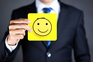 Businessman hold a happy face icon drawn on paper, Customer experience and satisfaction survey...