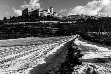 View of Assisi town (Umbria) in winter, with a field covered by snow and sky with white clouds