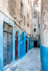 An alley of the Mellah district in Essaouira, Morocco. The lower dilapidated walls of the buildings...