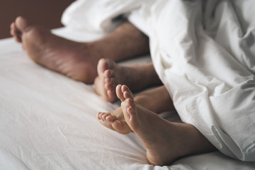 Close-up of the feet of a couple on the bed. Couples make love and sleeping on bed.