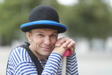 Portrait of a clown man in a suit and hat on a city street