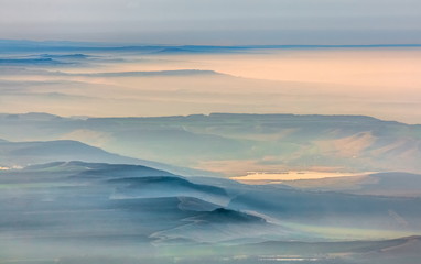 Mountains in the fog, haze. The Main Caucasian Range. Multicolored background. Mountains at sunset. Winter fog.