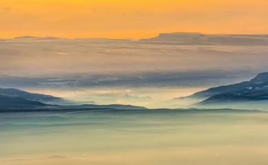 Mountains in the fog, haze. The Main Caucasian Range. Multicolored background. Mountains at sunset. Winter fog.