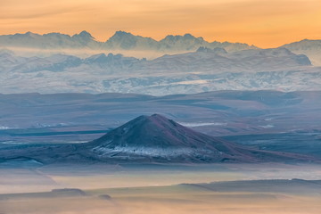 Mountains in the fog, haze. The Main Caucasian Range. Multicolored background. Mountains at sunset. Winter fog.