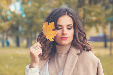 Young woman walking in autumn park and dreaming outdoors. Romantic portrait, autumn coming concept