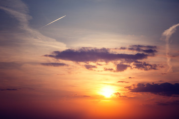Bright beautiful sunset sky, abstract background and texture, a trace from an airplane in the sky