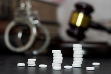 Judge's gavel with handcuffs, drugs on wooden table