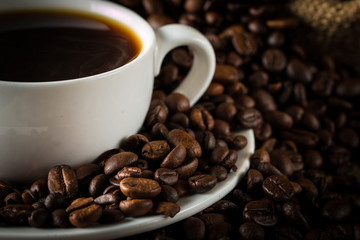 Coffee cup and beans on a rustic background. Coffee Espresso and a piece of cake with a curl. Cup of Coffee and coffee beans on table.