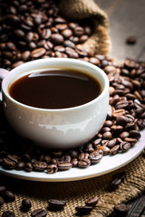 Coffee cup and beans on a rustic background. Coffee Espresso and a piece of cake with a curl. Cup of Coffee and coffee beans on table.