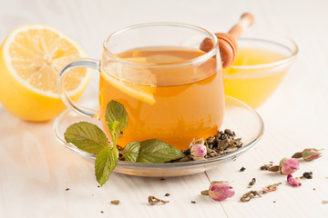 Closeup of cup of tea with tea leaves, mint on vintage wooden background. Black herbal tea with...