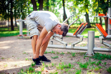 A man feeling pain in his foot during sport and workout in the park. Sport, medicine and people concept