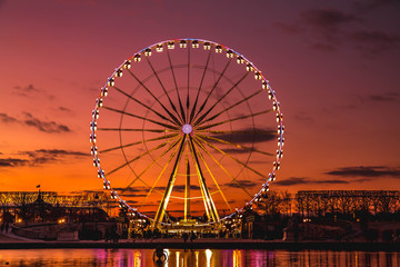Illuminated ferris wheel with colorful sunset. - Powered by Adobe