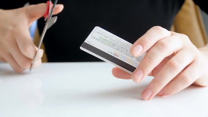 Closeup 4k footage of young woman cutting credit card with scissors. Problems with bank and bankruptcy