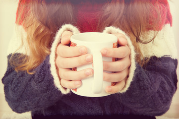 The girl is holding a cup of coffee.