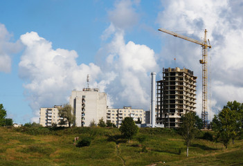Fototapeta na wymiar The basis of a house under construction, a working tower crane against the blue sky in summer weather.
