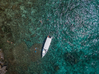 People Snorkeling in Tropical Sea near Yacht. Aerial View