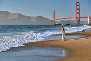 Woman walking on beach near Golden Gate Bridge