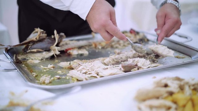 Catering food - professional chef in a restaurant or hotel kitchen preparing fish. Close-up of chef hands cooking. Cattering buffet offering delicious menu for any occasion. 4K (UHD).